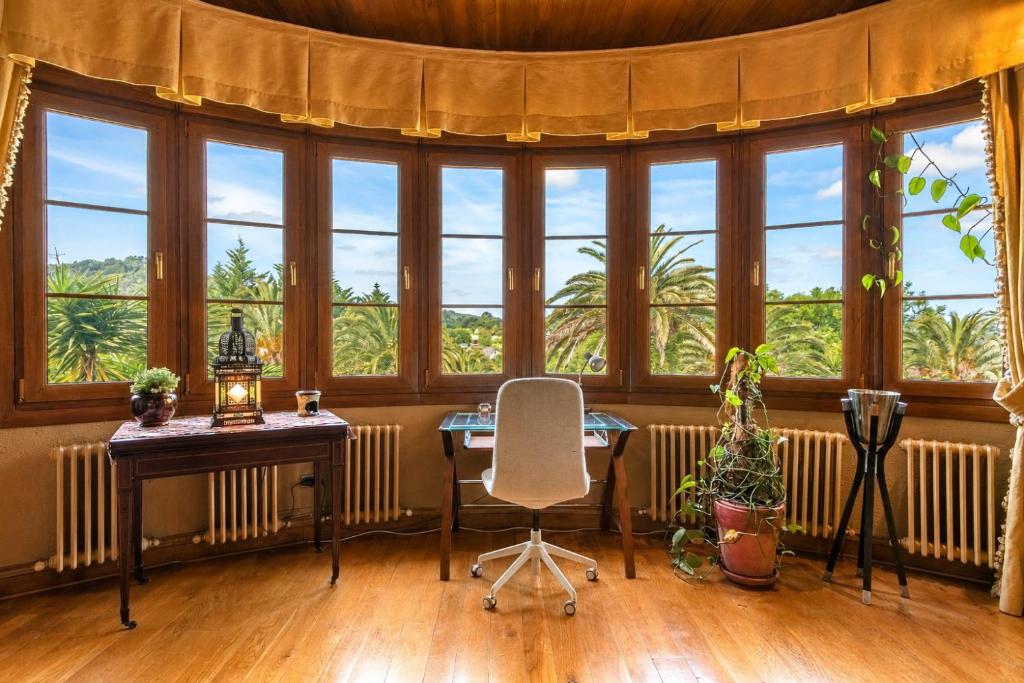 a room with windows and a table and a chair at Basque Palace, Mansion con Jardín, Barbacoa, Gimnasio, Piscina, Sauna in Mungia