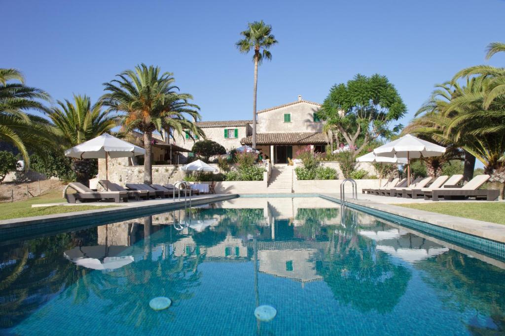a swimming pool with palm trees and a house at Monnàber Vell in Campanet