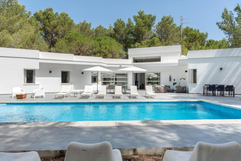 a villa with a swimming pool and chairs at Can Drago in Ibiza Town