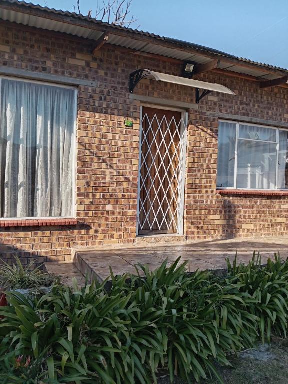 a brick house with a window and some plants at Benema's Rest in Waterval Boven