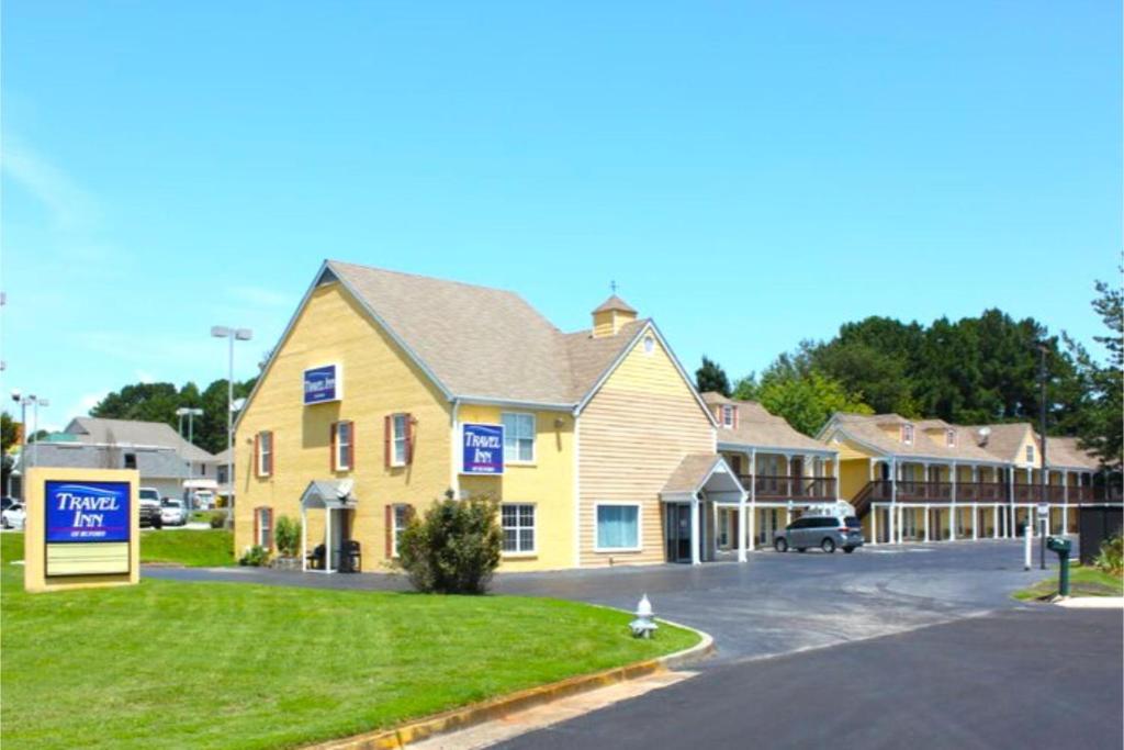 a building with a parking lot in front of a motel at Travel Inn Buford near Mall of Georgia in Buford