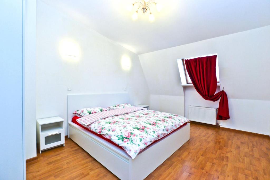 a white bedroom with a bed and a red curtain at La Casa Di Bury Apartments 1 in Saint Petersburg
