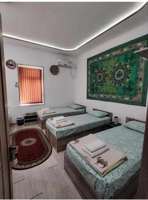 a room with three beds and a window and a rug at KAMIR Guest House in Bukhara