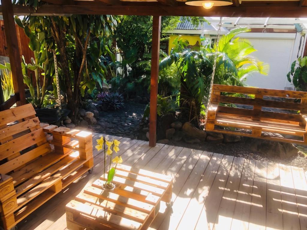 a patio with two wooden benches and plants at Appartement charmant à Basse-Terre - 25 m² avec jardin in Basse-Terre