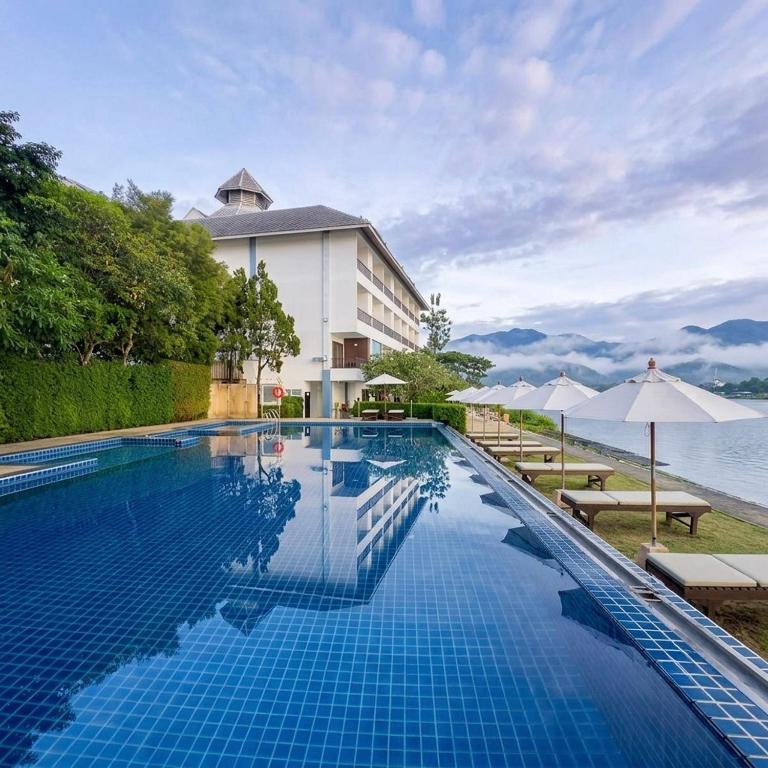 a pool at the resort with tables and umbrellas at Siam Triangle Hotel Chiang Sean in Chiang Saen