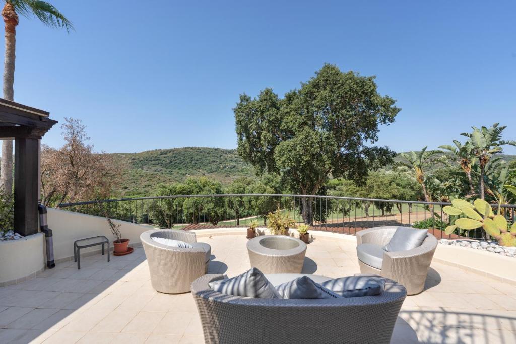 a patio with couches and chairs on a balcony at San Roque Golf Apartment in San Roque