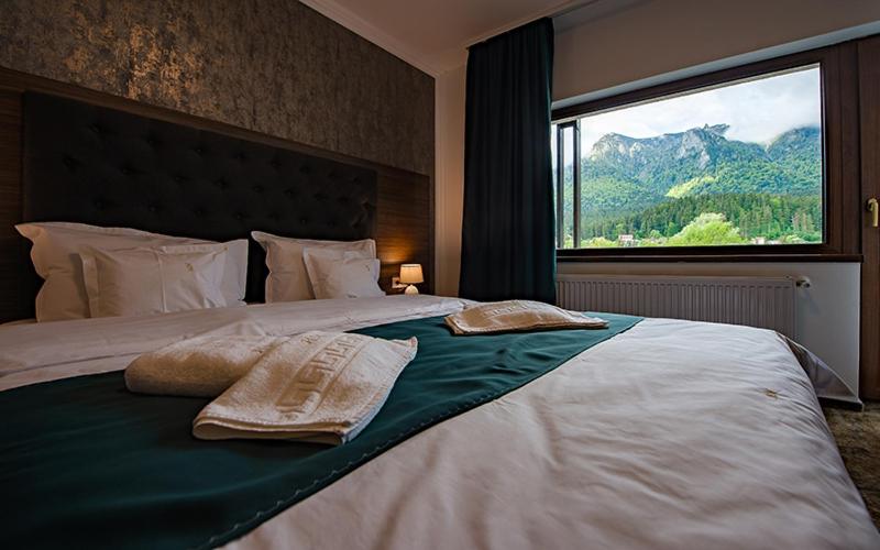 a bedroom with a large bed with two towels on it at Hotel Margaritar in Buşteni