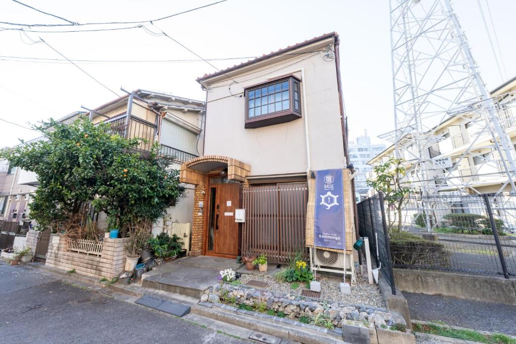 a white house with a wooden door on a street at Kamenoya, 羽田空港&ディズニー直通バス,2トイレ,亀有駅徒歩7分 in Tokyo
