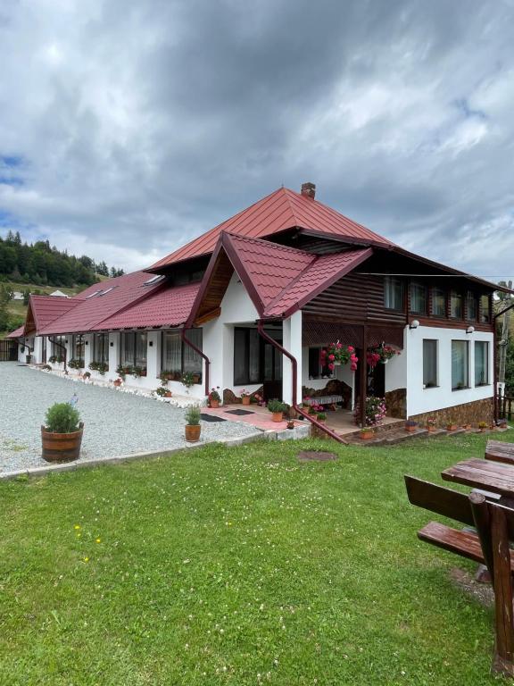 a house with a red roof and a green yard at Popas Turistic Gyl in Arieşeni