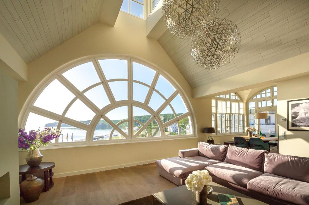 a living room with large windows and a couch at Strandschloss Binz - Penthouse "Royal Beach" mit Sauna, Kamin, Terrasse, Meerblick in Binz