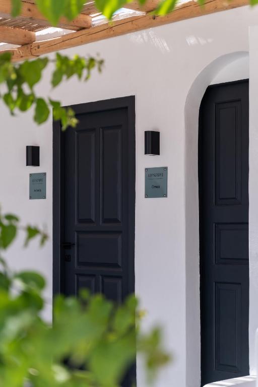 two black doors on the side of a white building at Ornos Collection - by Hospirit in Ornos