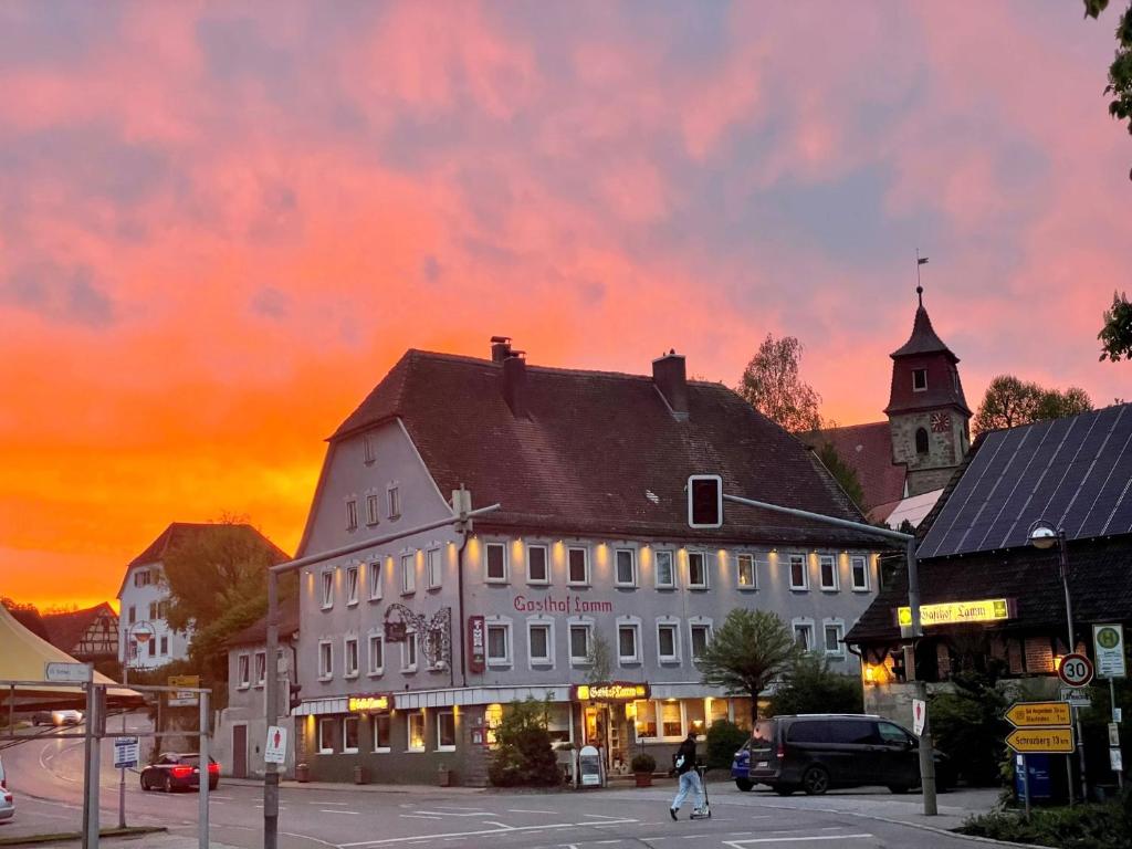 a building in a town with a sunset in the background at Hotel-Gasthof Lamm in Rot am See
