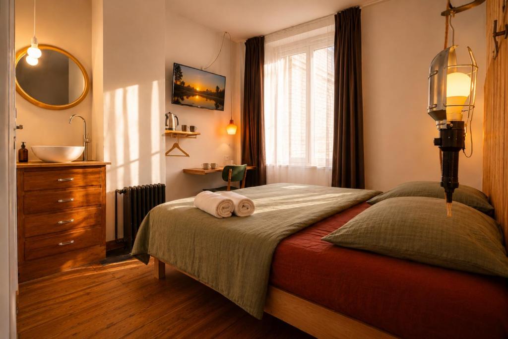 a bedroom with a bed with two towels on it at LA MAISON FIVES - Esprit Hôtel Design - Lille in Lille