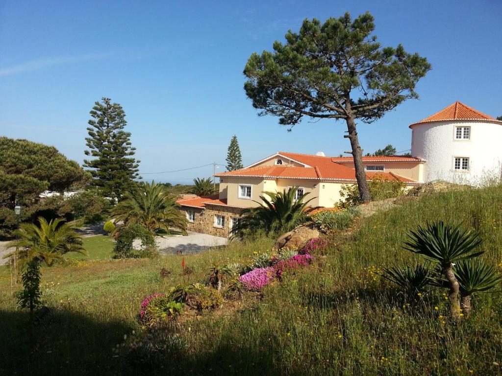 a house on a hill with a tree and flowers at Quinta do Cabo Guesthouse in Sintra
