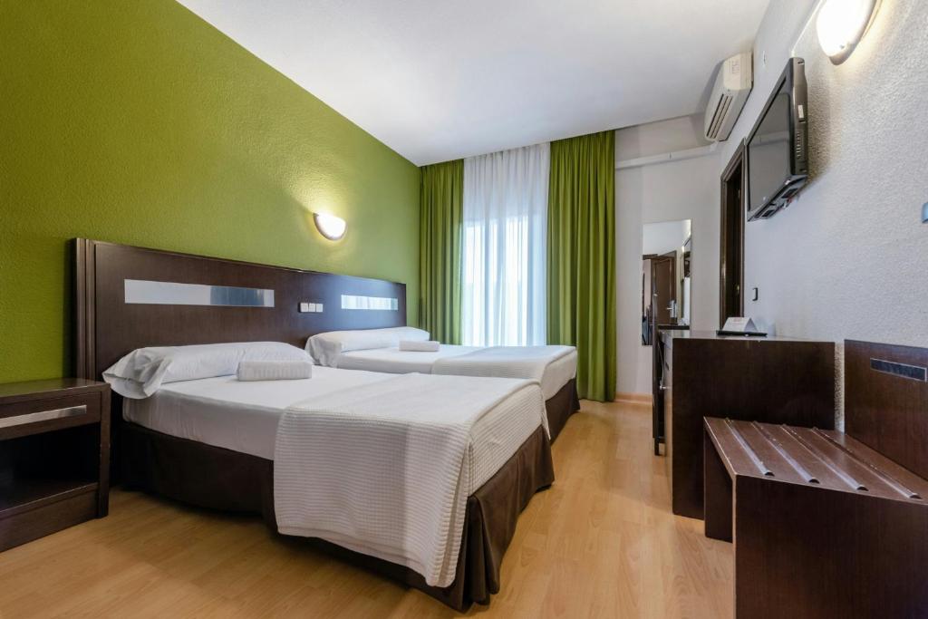 a bedroom with two beds and a green wall at Sercotel Las Estrellas in Ciempozuelos