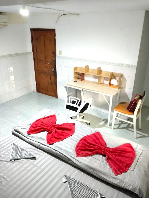 a bed with red sheets and a desk in a room at Home Frog Guesthouse in Phnom Penh