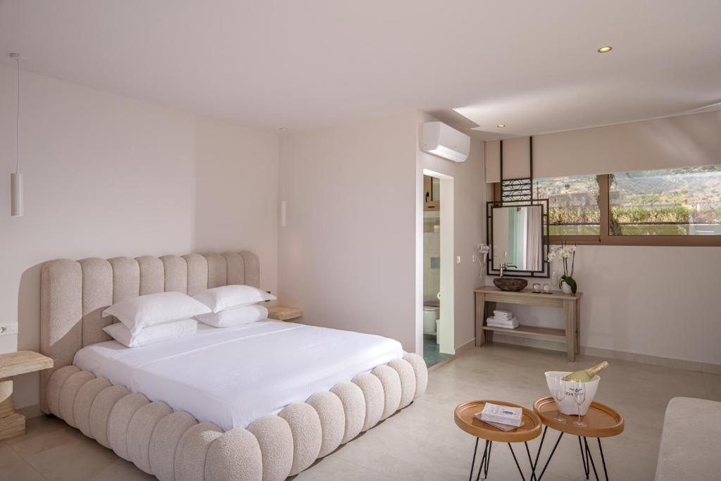 a bedroom with a large white bed and a television at Parthenis Hotel & Suites in Malia