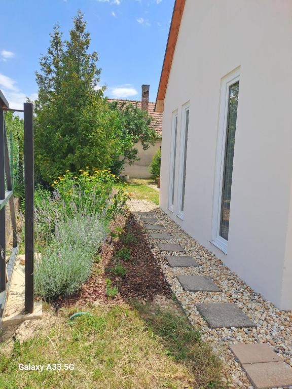 a walkway next to a white house with some plants at Garden House in Dég