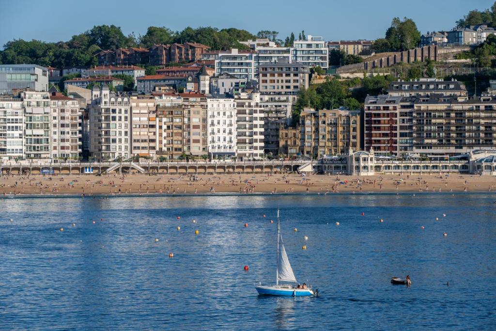 a sailboat in the water in front of a beach at Hotel Niza in San Sebastián