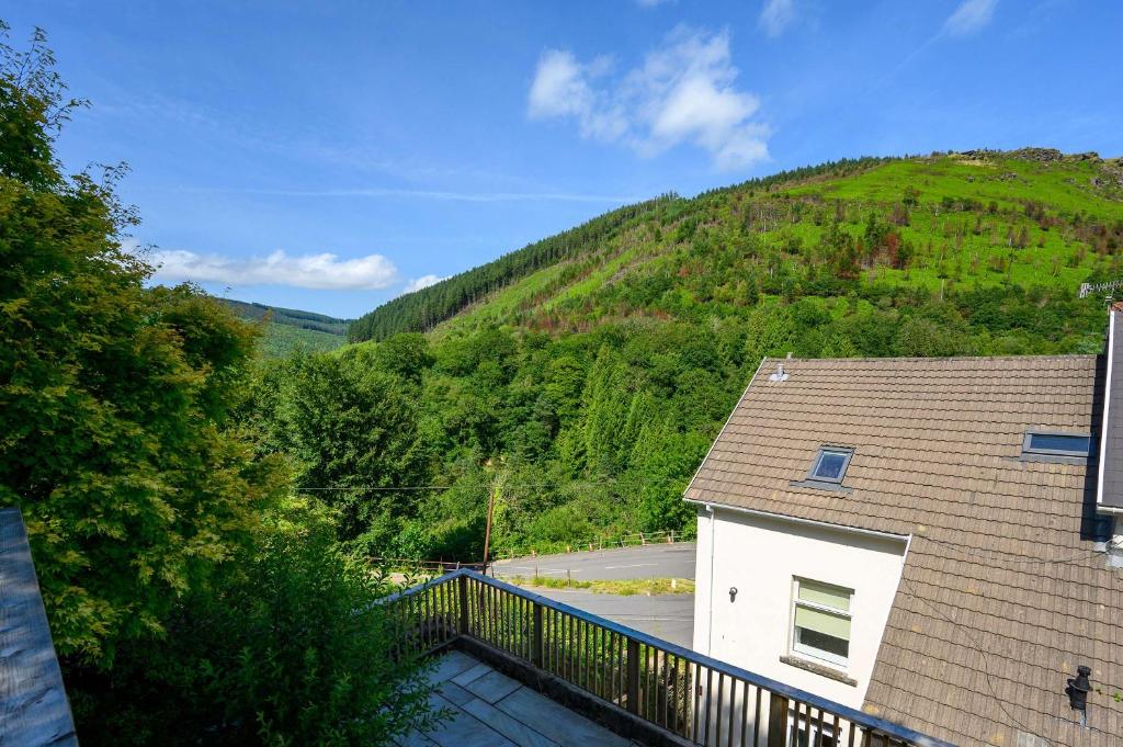 a house with a balcony with a mountain in the background at Maesteg Road - Large House - Sleeps 10 - Gateway to Afan Forest and Bike Trails in Dyffryn