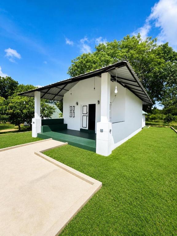 a small white house with a green lawn at Green Techno Villa in Kitulkote