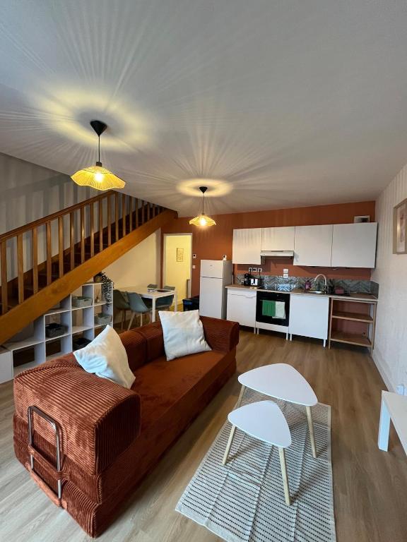 a living room with a brown couch and a kitchen at Maison cozy in Saint-Brieuc