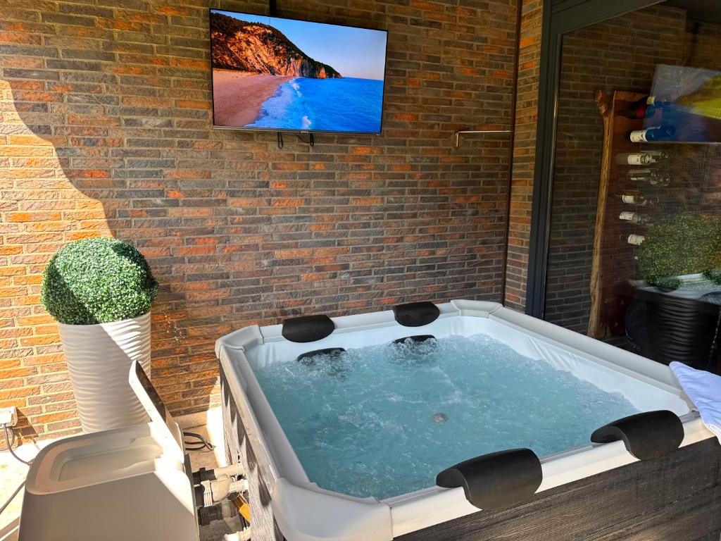 a bath tub with a tv on a brick wall at Emotion Apartments- Erlebnis Apartment mit privater Sauna und Whirlpool in Vlotho