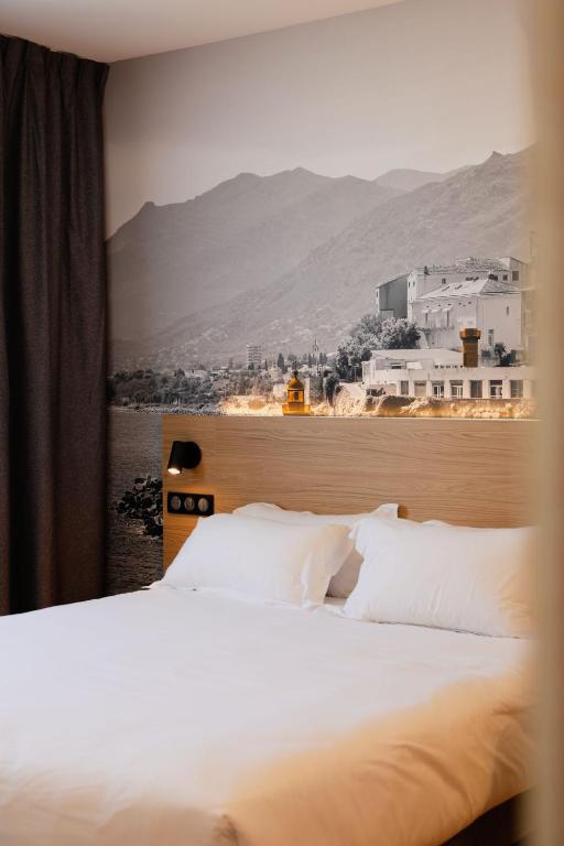 a bed with white pillows in a room with a view at B&B HOTEL Bastia in Bastia