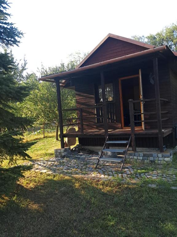 a log cabin with a porch and a chair in the yard at Kemp pro karavan a stan s chatkou in Veselí nad Moravou