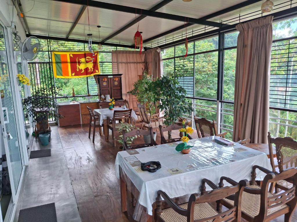a dining room with a table and chairs and windows at Sunset Inn in Kandy