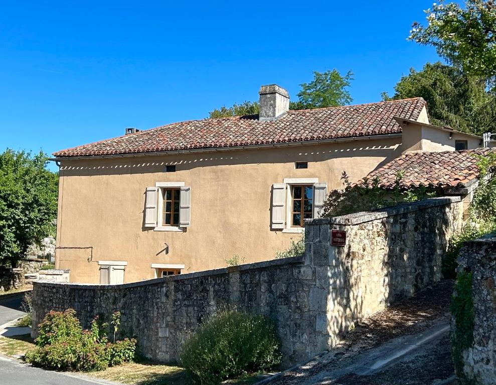 a house with a stone fence in front of it at La Maison des Sources in Édon