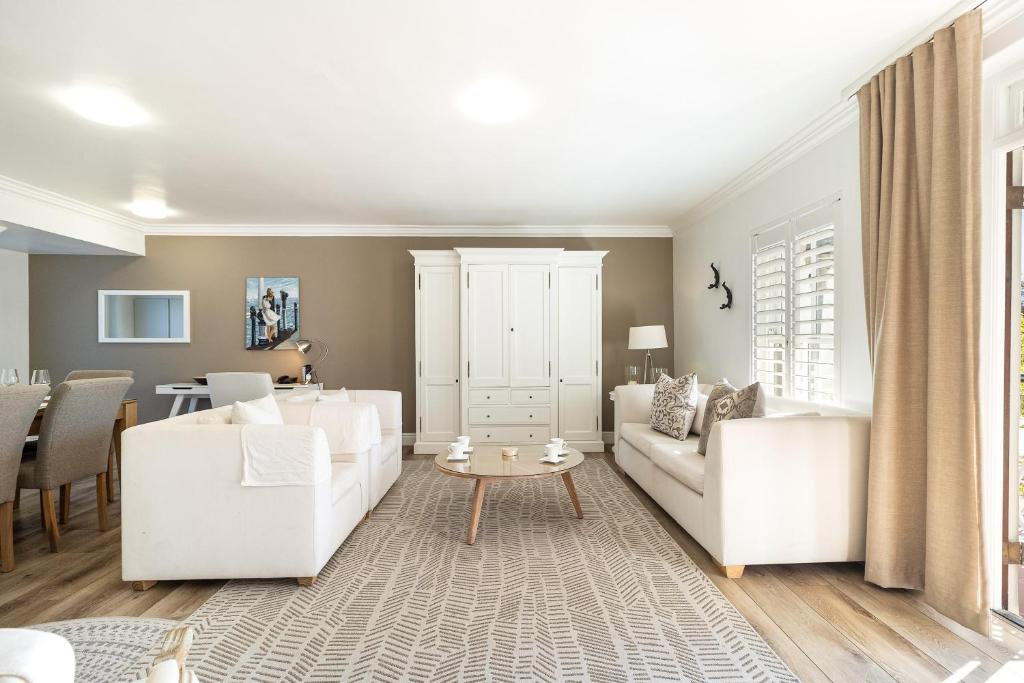 a living room with white furniture and a table at Winelands Golf Lodges 28 in Stellenbosch