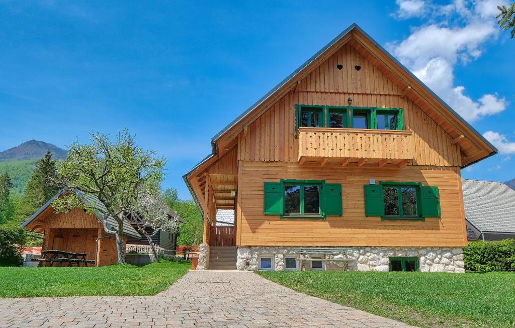 a large wooden house with green shuttered windows at Cottage Suha in Bohinj