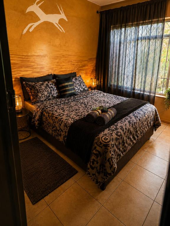 a bedroom with a bed and a window at Bushman Kraal Backpackers in Soweto