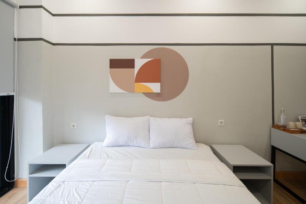 a bedroom with a white bed and a painting on the wall at Cove Atman in Jakarta