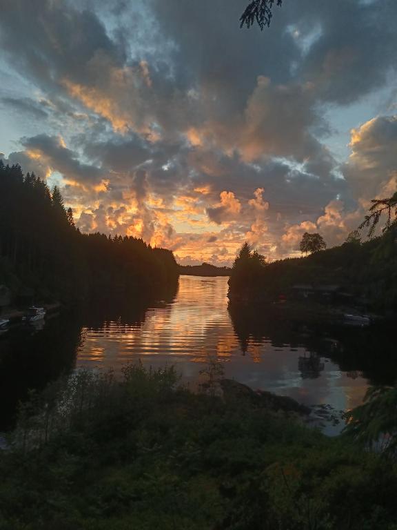 a sunset over a river with the sun setting at Vakker perle nær sjøen in Villanger