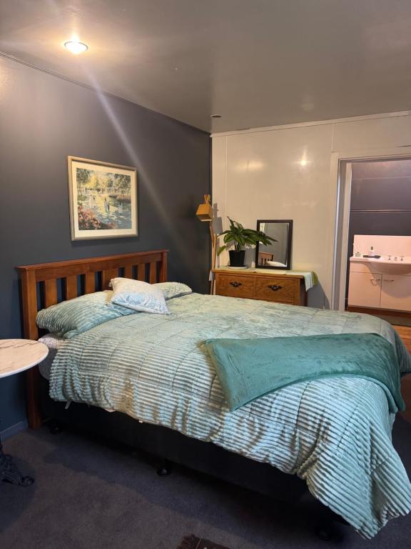 a bedroom with a bed with a green comforter at AB Accomodation in Palmerston North
