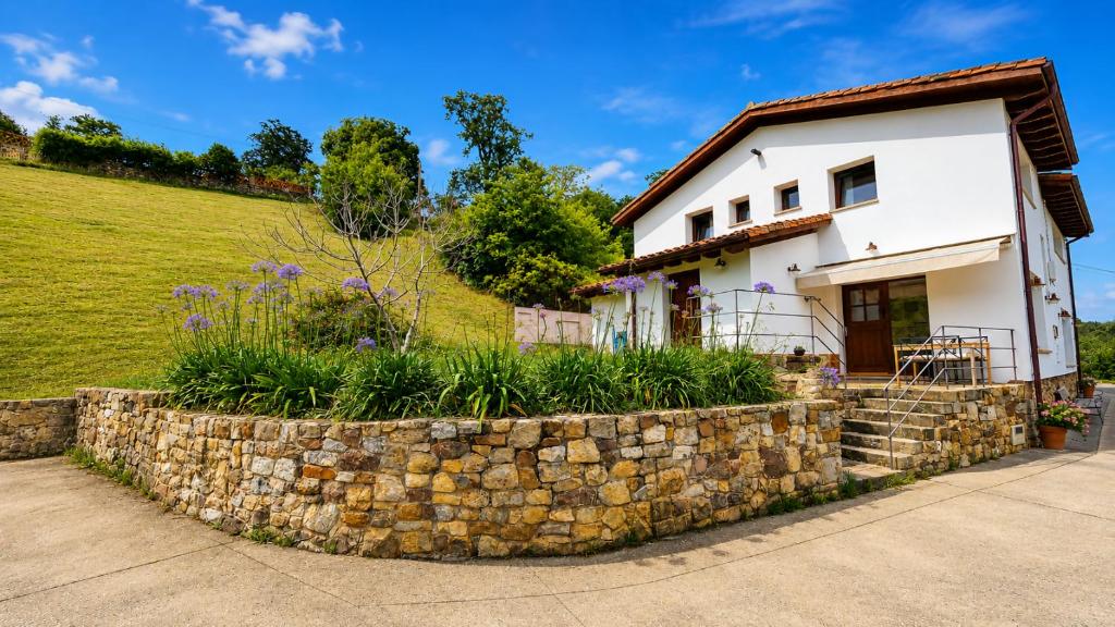 a white house with a stone wall at La Cuadra de San Pedro Ribadesella in Ribadesella