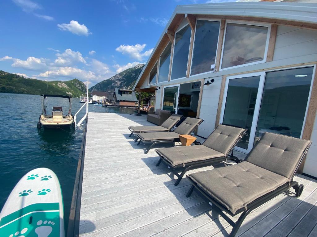a dock with chairs and a boat on the water at Viridian Three Boathouse Unique, PERUCAC in Perućac