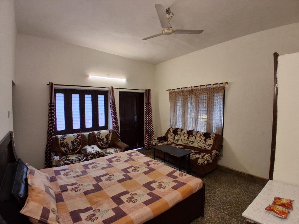 a bedroom with a bed and a couch and a fan at Sandy Homestay in Dehradun