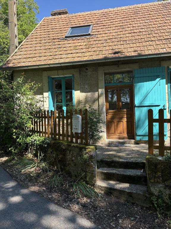 a blue house with a wooden door and a fence at Cottage de La Meslerie in Vernou-sur-Brenne