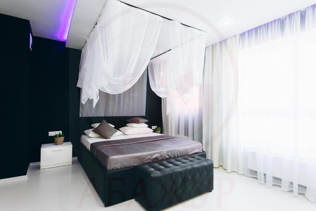 エカテリンブルクにあるAbazhur Apartment Ekaterinburg Yumashevaのベッドルーム(白いカーテン付きの大型ベッド1台付)