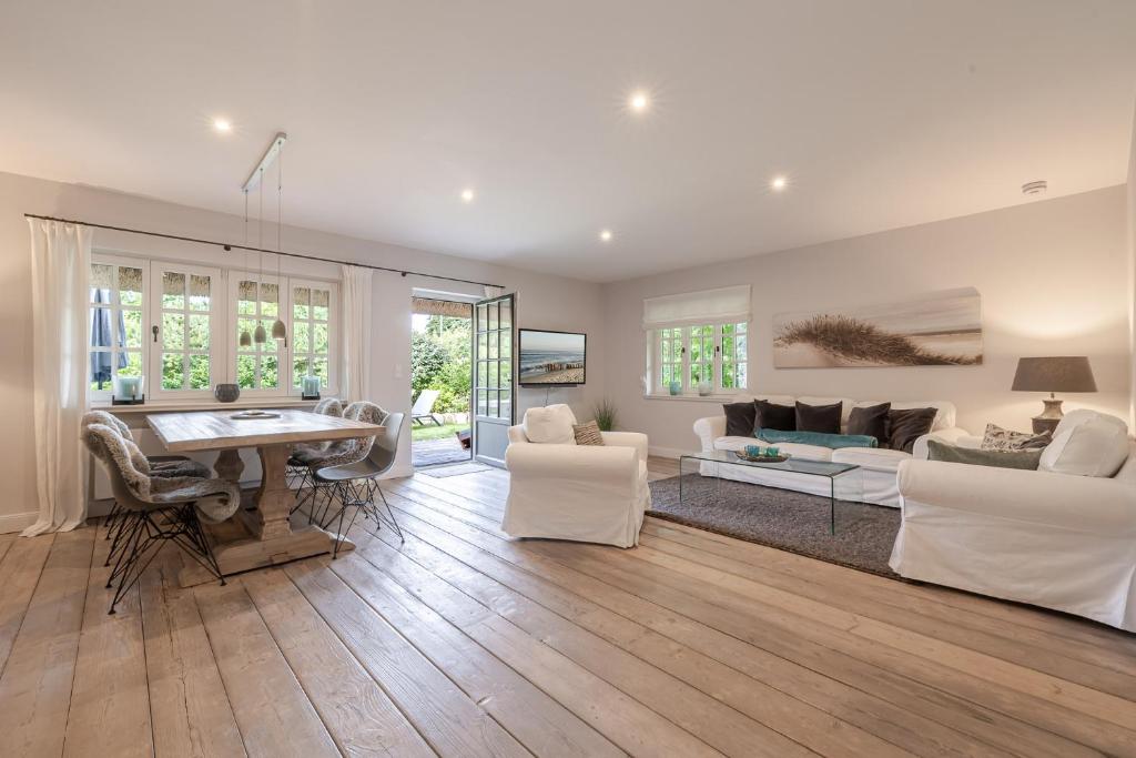 a living room with white furniture and a table at Sommerhaus in Keitum