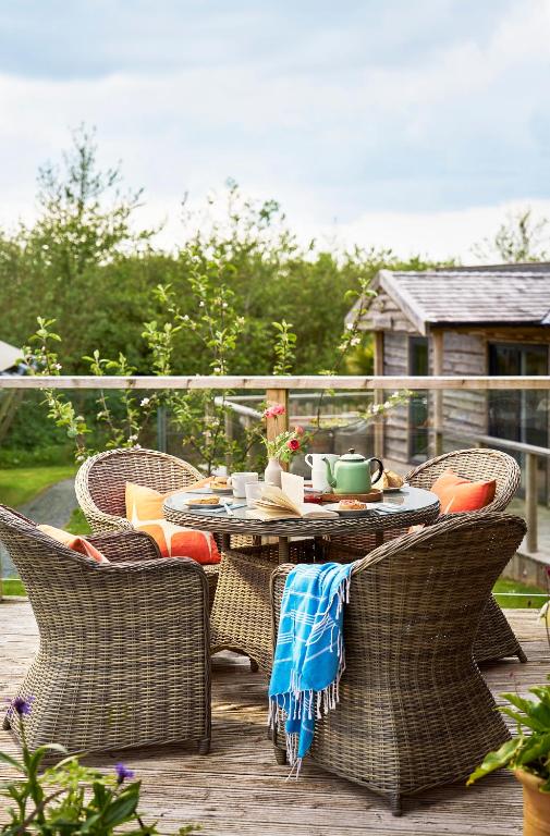 a patio with a table and chairs on a deck at The Pig Arc in Bude