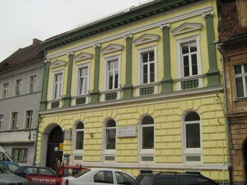 een geel en groen gebouw met auto's geparkeerd voor het bij Casa Terezia in Braşov