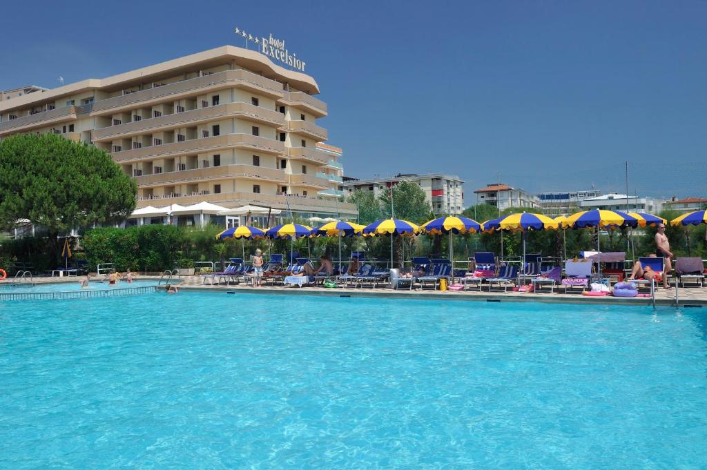 a beach with a pool, chairs, and umbrellas at Hotel Excelsior in Bibione