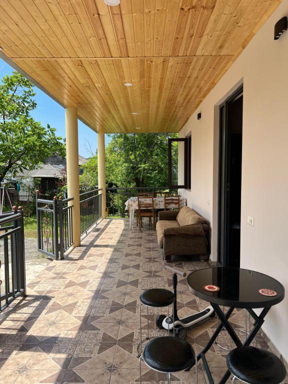 a patio with a wooden ceiling and a table and chairs at Sea Breeze House Ureki in Ozurgetʼi