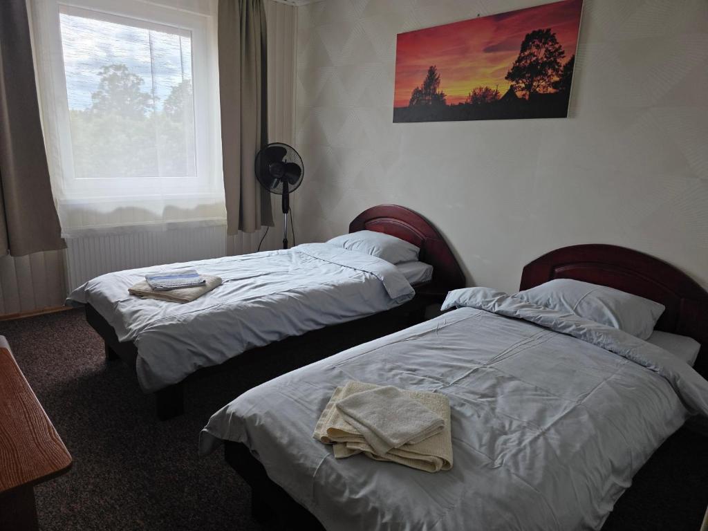 two beds in a hotel room with towels on them at Gintagnė in Aleksandrija