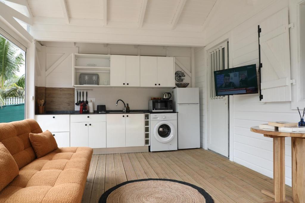 a kitchen with white cabinets and a washing machine at Joli Cocon in Baie-Mahault