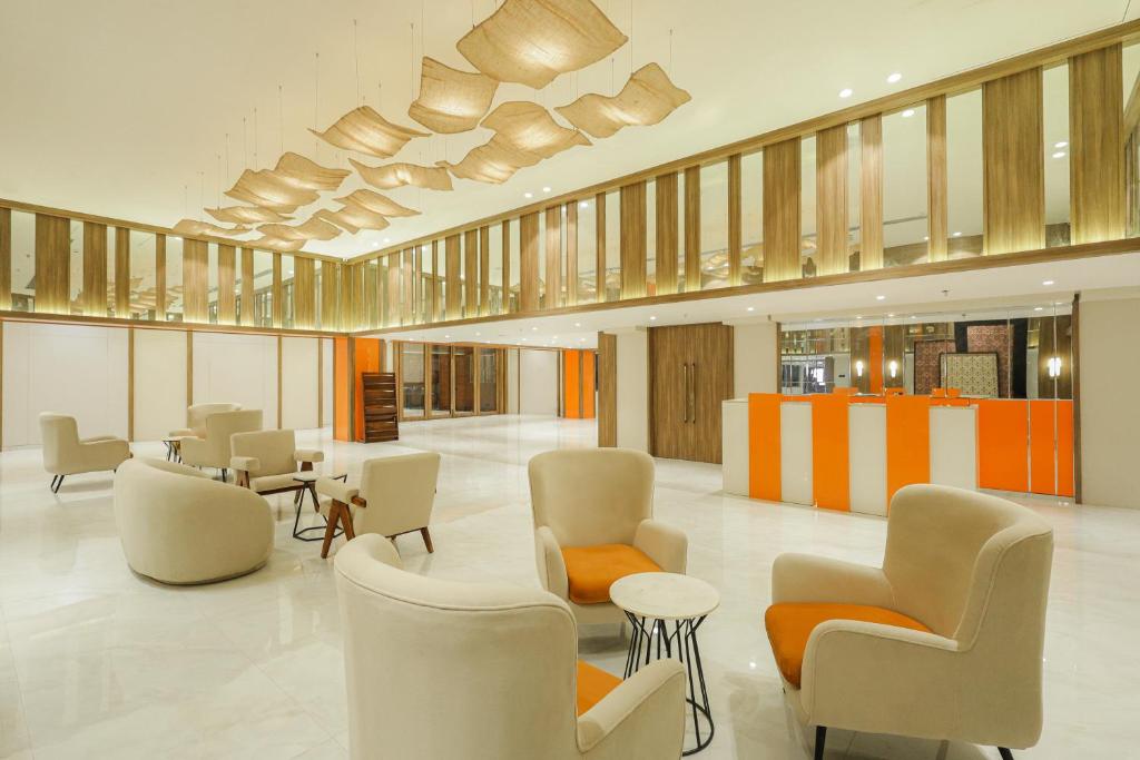 a lobby with chairs and tables in a building at Ira By Orchid Bhavnagar in Bhavnagar